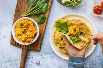 Chapati Indian flatbread. Traditional round bread. Fresh green salad and red dal lentil stuffed naan. Vegan, vegetarian healthy food. Hands make vegetable wrap