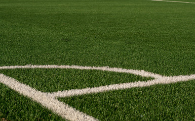 Artificial green grass and white border lines. Artificial turf for soccer field. Football field in an outdoor stadium. Selective focus