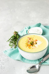 Thick milky chowder soup with seafood served with sour cream, thyme and pepper. Light grey stone background. 