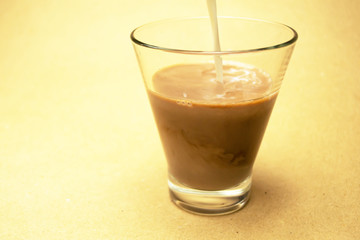 Milk is poured into a glass glass with cocoa