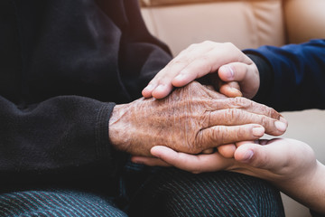 Young man's holding older grandmother hands feel with love and support together, Care for elderly Helping hands, take care concept.