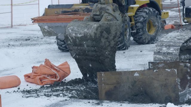 Excavtor levels dirt to fill hole on snowy winter day - construction - close up