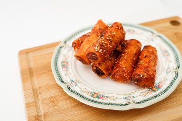 A plate of spicy and sweet fried spring rolls.  Stacked in a plate isolated on white background.  The cuisine is also known as Popiah Goreng Sambal in Malay