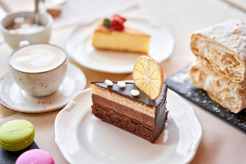 Breakfast in the cafe, morning coffee. Cappuccino and lots of desserts on the table. Napoleon, chocolate cake, cheesecake and macaroons.