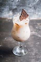 Creamy cocktail with ice and slice of chocolate. Selective focus. Shallow depth of field.