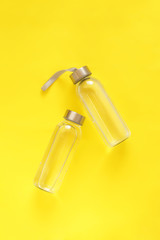 Glass bottles with a metal lid with water on a yellow background. 