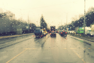 dense traffic on a rainy day. Traffic in rainy day with road view through car window with rain drops. Blurry image, Rain drops on car windshield, traffic in the city on a rainy day. Selective focus