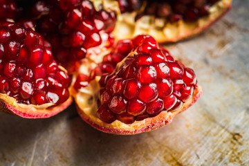 Broken red ripe pomegranate fruit on the dark rustic background. Selective focus. Shallow depth of field.