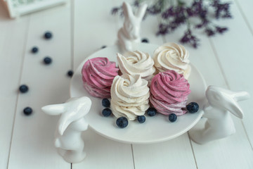 beautiful delicate marshmallows lie on a beautiful plate held by porcelain hares