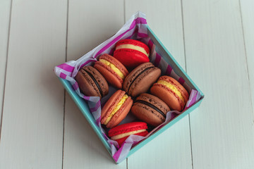 Gift set of sweets from macarons and marshmallows beautifully photographed in a box on a white wooden table with flowers
