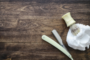 Shaving accessories on a wooden texture background. Tools. Disposable shaving machine, brush, foam and hazard razor.