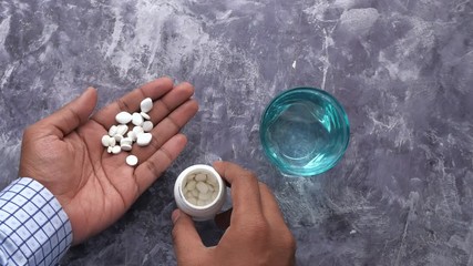 top view of person taking pills and water glass on table  - Powered by Adobe