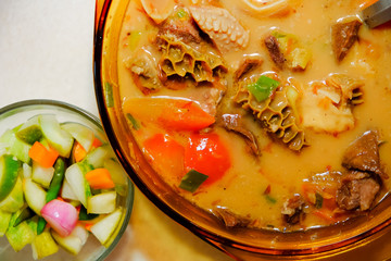 A bowl of Soto Betawi, Indonesian native traditional soup made of beef or beef offal cooked in coconut milk broth, to be eaten along with pickles