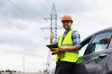 A man in a helmet and uniform, an electrician in the field. Professional electrician engineer...