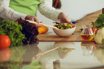 Unknown human hands cooking in kitchen. Woman is busy with vegetable salad. Healthy meal, and vegetarian food concept