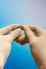 Close-up of hands in rubber gloves holding an open ampoule with a vaccine