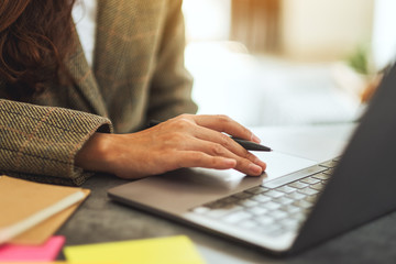 Businesswoman writing and typing on laptop computer on the table in office