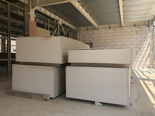 Piled sheets of drywall at the construction site. Stacked plasterboard sheets. Gypsum cardboard