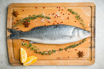 Raw whole seabass fish on the rustic background. Selective focus. Shallow depth of field.