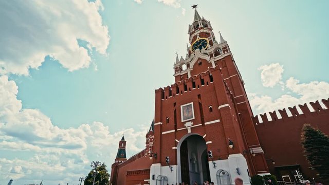 Slow-motion orbital shot of the Kremlin eastern wall as the sun peeks out from behind the Spasskaya Tower, creating a lens flare. 
