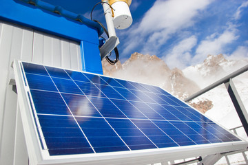 Solar panel in mountain lake on blue sky background. Alternative energy concept.