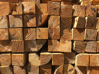Stack of lumber at the outdoor warehouse. Stacked wooden beams of square section