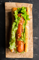 Tasty fresh hot dogs with grilled sausage, french mystard and fresh salad leaves on the rustic background. Selective focus. Shallow depth of field.