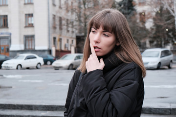 Fototapeta premium thoughtful teenage girl is watching on cars background in spring city background. Girl decided to buy something