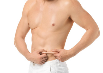 Handsome young man touching fat on his belly against white background. Plastic surgery concept