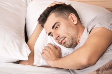 Fototapeta na wymiar Depressed young man in bedroom