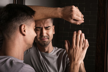 Depressed young man near mirror