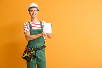Handsome male worker with tablet computer on color background