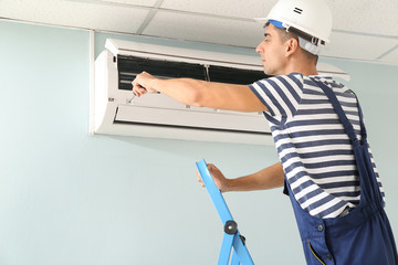 Male technician repairing air conditioner indoors