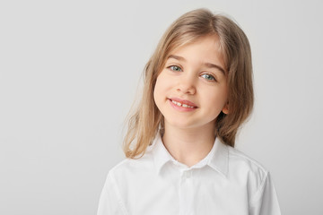 Fototapeta premium Happy little girl with healthy teeth on light background