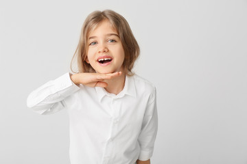 Happy little girl with healthy teeth on light background