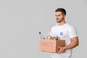 Volunteer with donations for poor people on light background