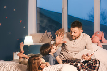 Father and his little children reading bedtime story at home