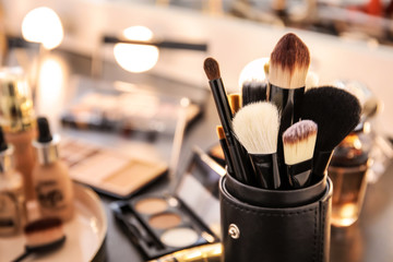 Brushes and different cosmetics on table of makeup artist - obrazy, fototapety, plakaty