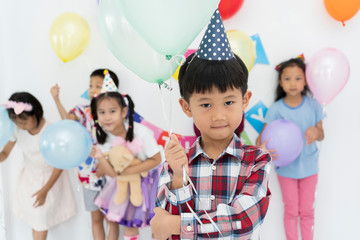 Fototapeta na wymiar Happy Asian little boy celebrating his six year birthday with friends in Living room smiling to camera. group of Asian ethnicity children model. concept of kids celebrate birthday party together