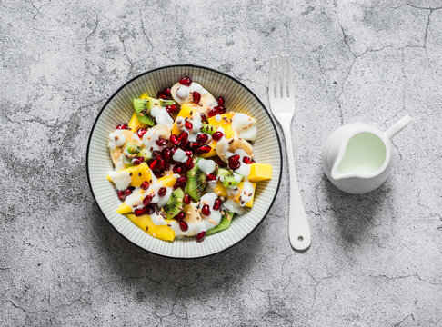 Coconut Yogurt And Tropical Fruit Salad For Breakfast, Snack, Dessert. Salad With Greek Yogurt, Banana, Mango, Kiwi, Pomegranate Seeds And Flaxseeds On A Gray Background. The View From The Top