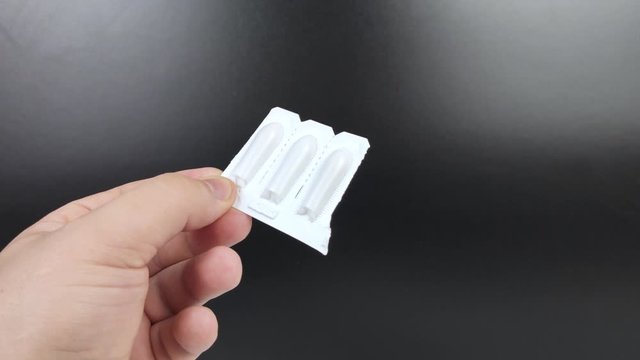 Suppositories in white packaging in the hands of a man. Macro video of rectal or vaginal suppositories before use.