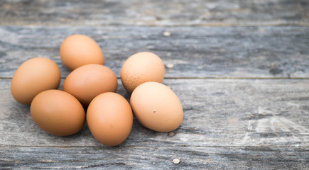 The chicken eggs are placed on the left in groups on the old wooden plate.