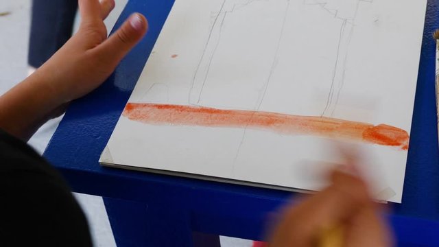 Girl learns to paint with watercolor paints. draws the orange lane