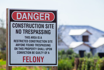 Venice FL December 29, 2019 - A large 'Danger Construction Site' sign is shown with a partially completed house in the background. The sign also states No Trespassing and Felony 