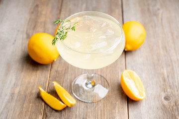 Tasty and little  bitter lemon cocktail with slice of fresh lemon and thyme. Selective focus....