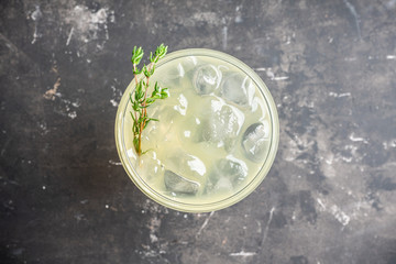 Tasty and little  bitter lemon cocktail with slice of fresh lemon and thyme. Selective focus. Shallow depth of field.