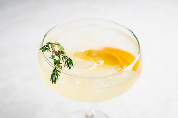 Tasty and little  bitter lemon cocktail with slice of fresh lemon and thyme. Selective focus. Shallow depth of field.