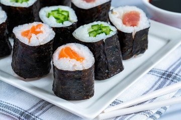 A selection of sushi rolls with salmon, tuna, cucumber and soy sauce dip.
