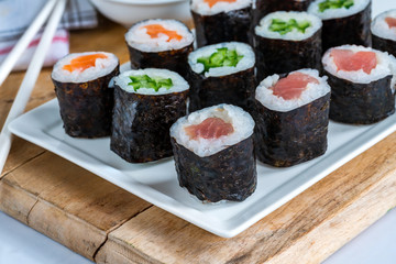A selection of sushi rolls with salmon, tuna, cucumber and soy sauce dip.