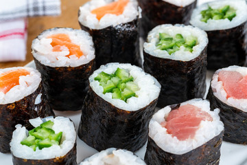 A selection of sushi rolls with salmon, tuna, cucumber and soy sauce dip.